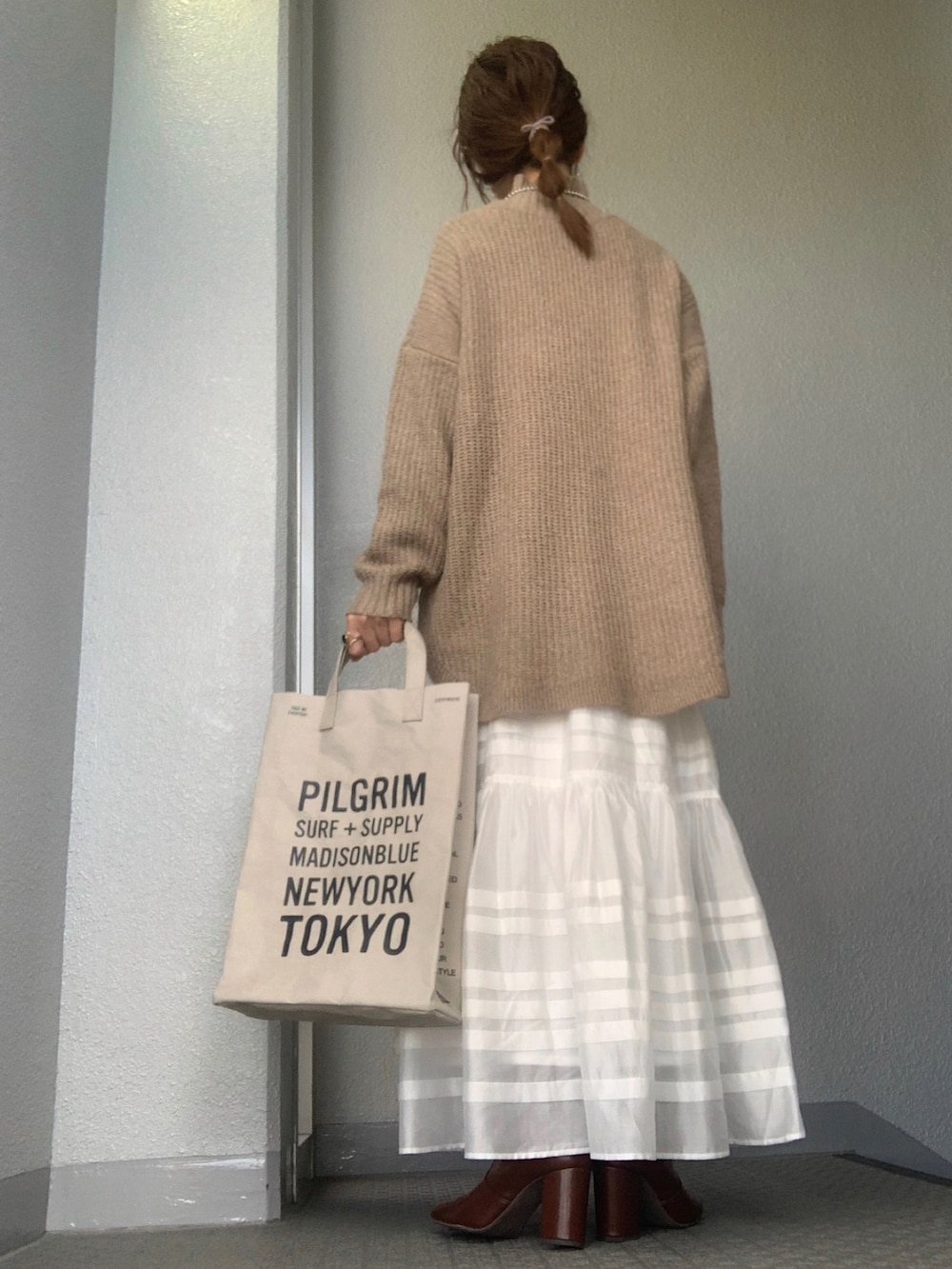 ブラウン系のニット/セーター、ホワイト系のスカート、ブラウン系のブーツを着用したレディースの冬コーディネートの3枚目の写真