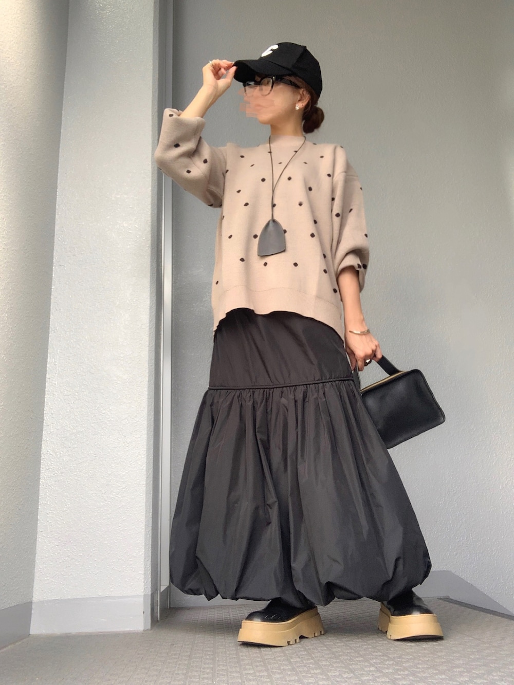 ベージュ系のニット/セーター、ブラック系のスカートを着用したレディースの秋コーディネートの2枚目の写真