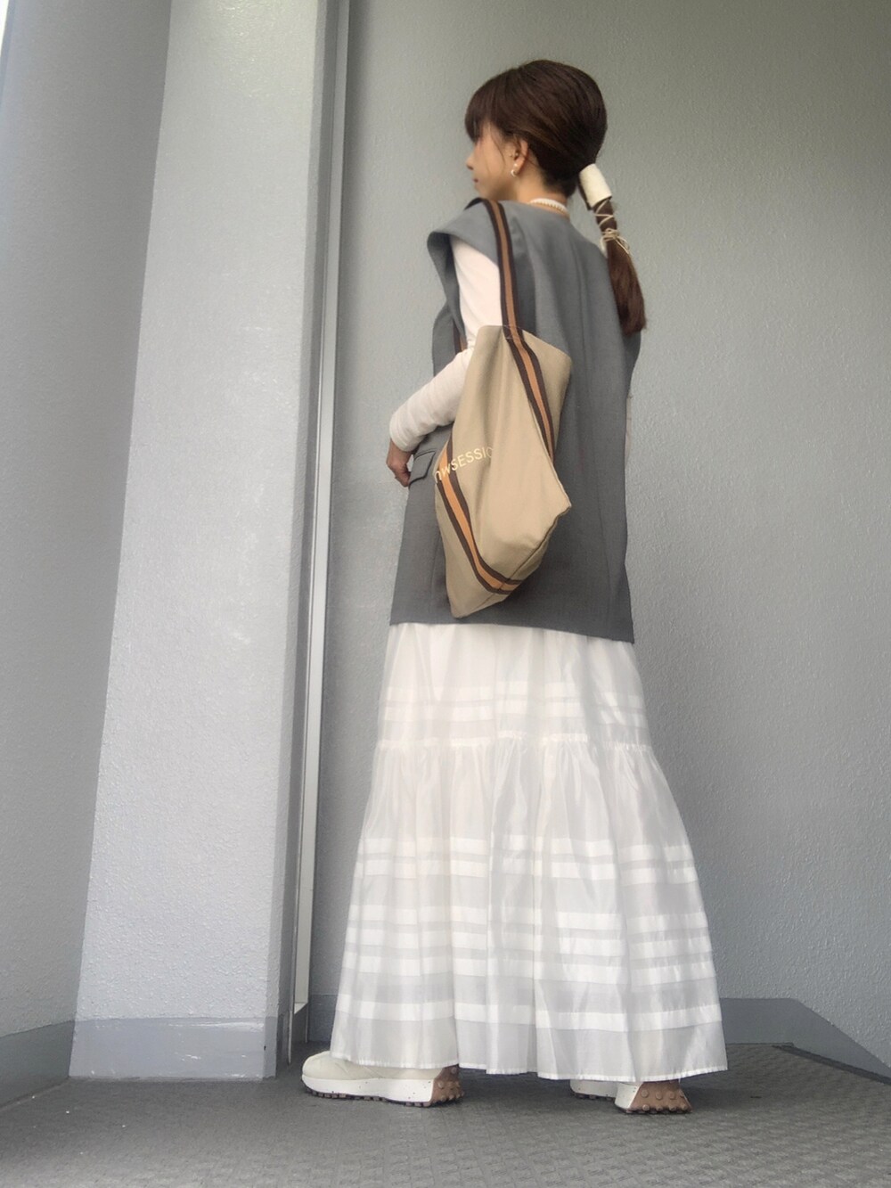 ホワイト系のスカート、ホワイト系のスニーカー、シルバー系のバングル/リストバンドを着用したレディースの春コーディネートの2枚目の写真