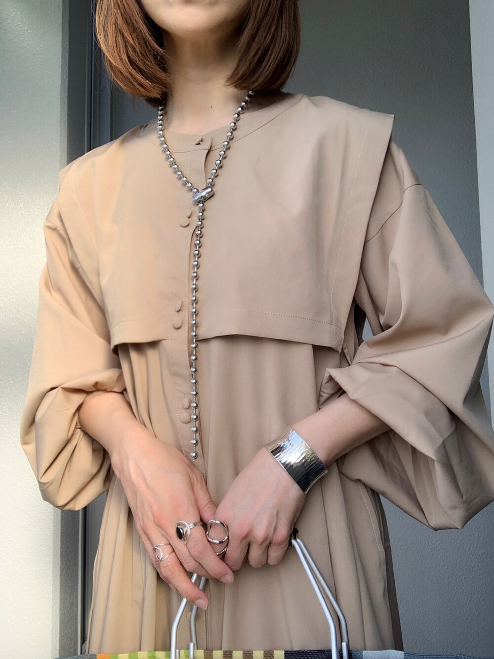 ベージュ系のシャツワンピース、その他のトートバッグ、ベージュ系のスニーカーを着用したレディースの春コーディネートの5枚目の写真