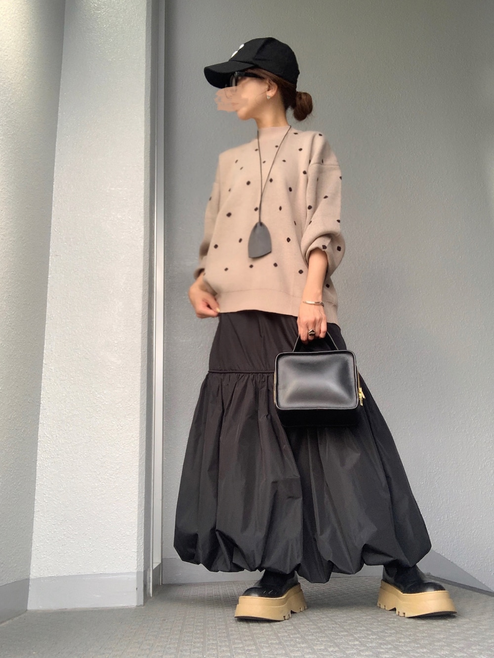 ベージュ系のニット/セーター、ブラック系のスカートを着用したレディースの秋コーディネートの3枚目の写真