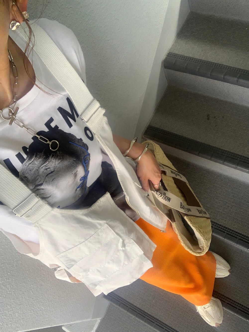 ベージュ系のトートバッグ、ホワイト系のベスト、ホワイト系のスニーカーを着用したレディースの春コーディネートの3枚目の写真