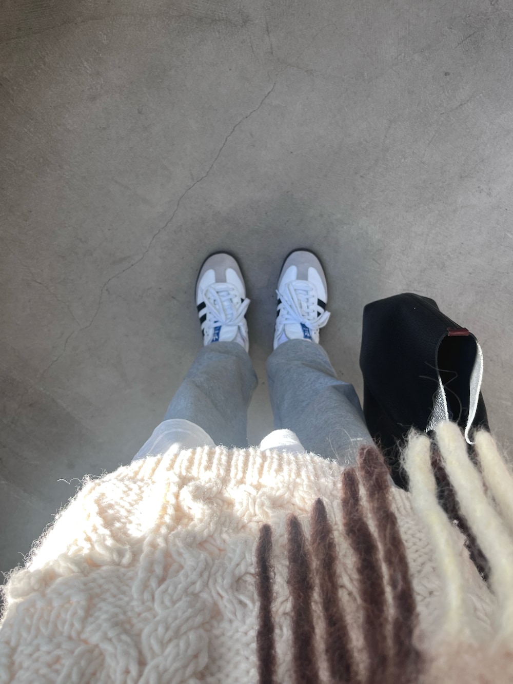 ホワイト系のニット/セーター、ブラック系のハンドバッグ、ホワイト系のスニーカーを着用したレディースの冬コーディネートの4枚目の写真