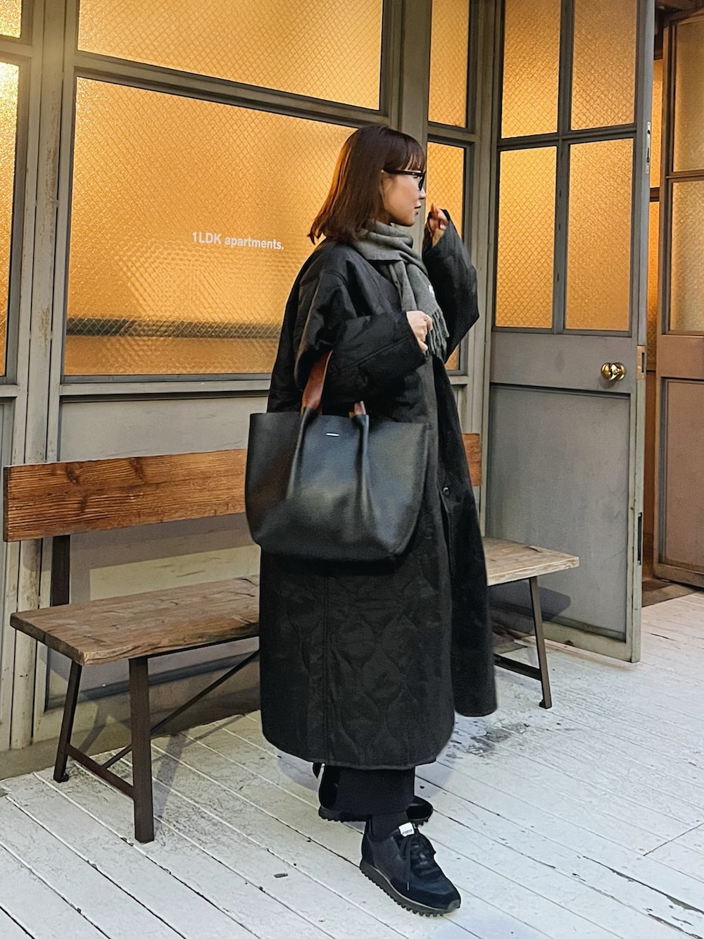 ブラック系のハンドバッグ、ブラック系のスニーカー、グレー系のマフラーを着用したレディースの春コーディネートの5枚目の写真
