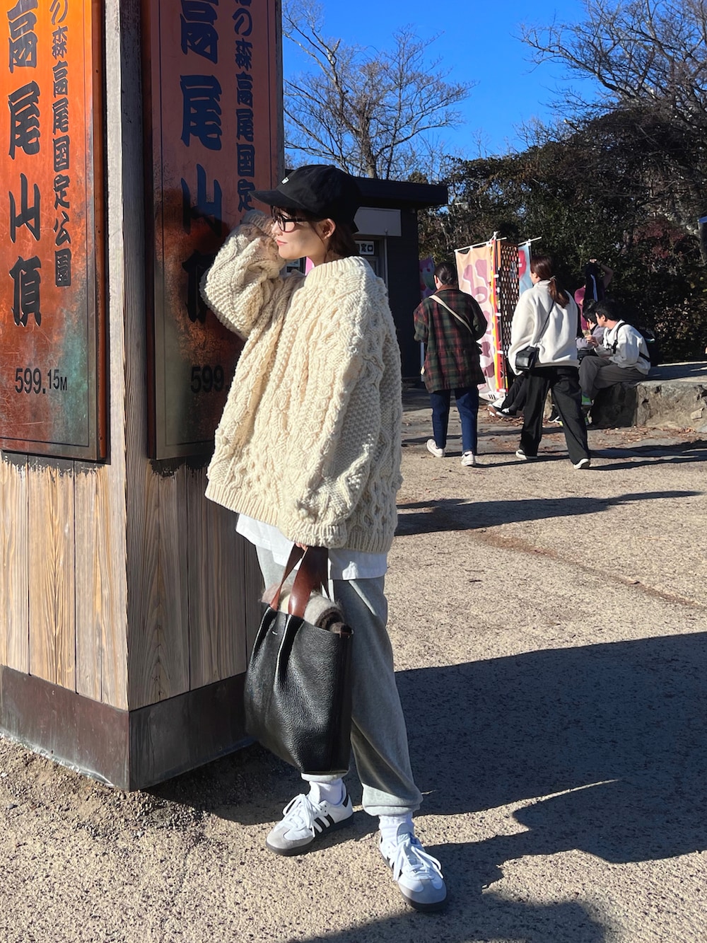 ホワイト系のニット/セーター、ブラック系のハンドバッグ、ホワイト系のスニーカーを着用したレディースの冬コーディネートの2枚目の写真