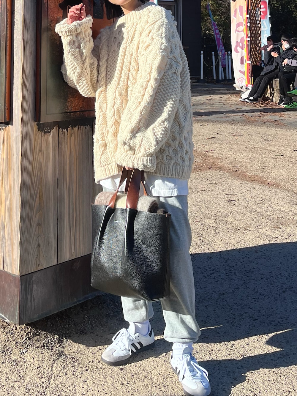 ホワイト系のニット/セーター、ブラック系のハンドバッグ、ホワイト系のスニーカーを着用したレディースの冬コーディネートの3枚目の写真