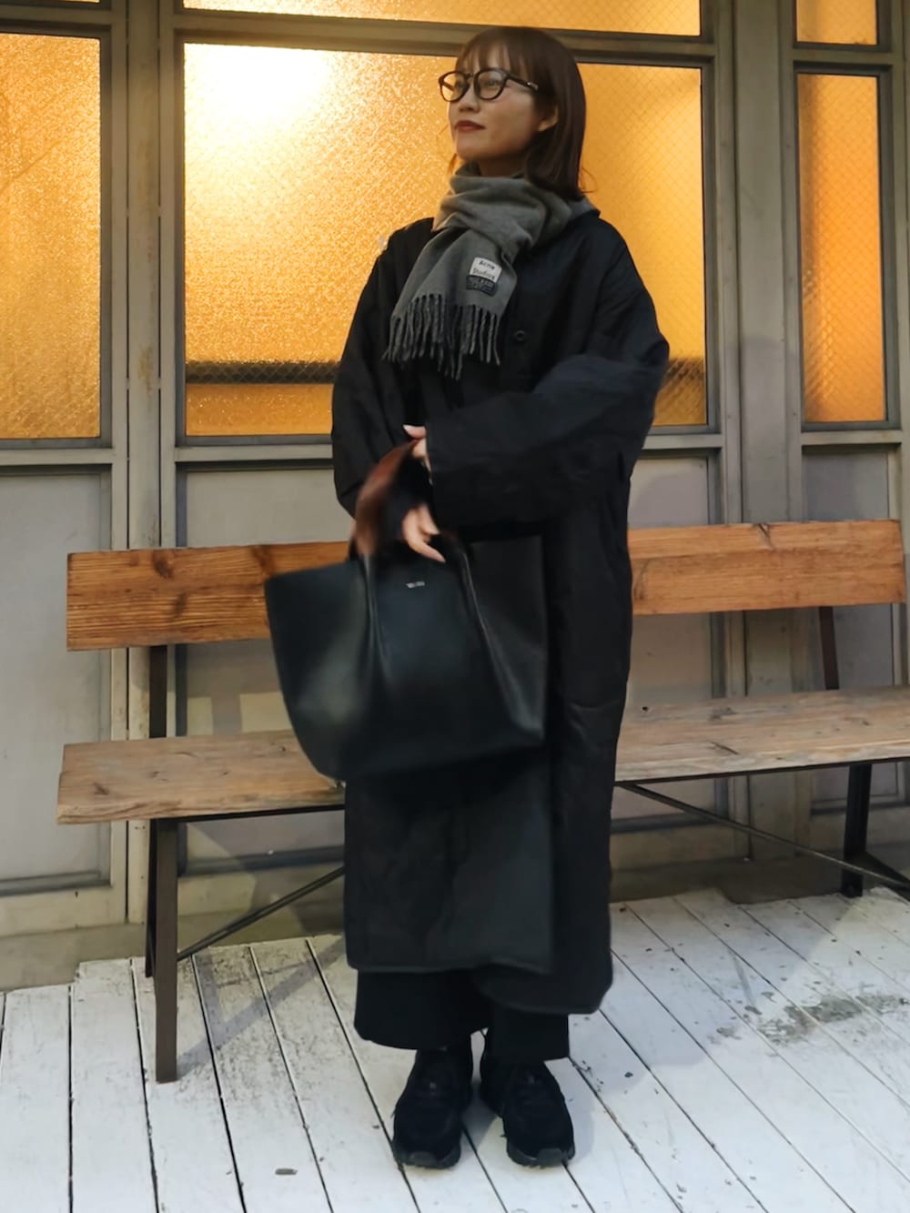 ブラック系のハンドバッグ、ブラック系のスニーカー、グレー系のマフラーを着用したレディースの春コーディネートの4枚目の写真