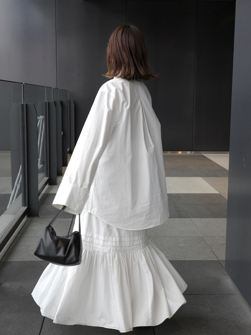 ホワイト系のシャツ/ブラウス、ホワイト系のスカート、ブラック系のハンドバッグを着用したレディースの春コーディネートの3枚目の写真