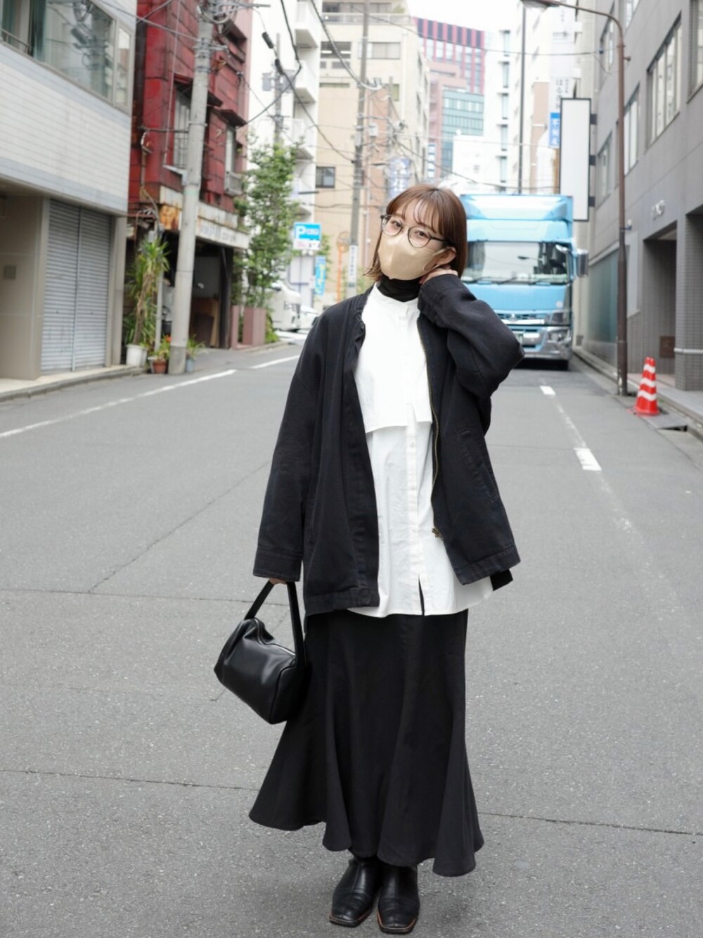 ブラック系のデニムジャケット、ブラック系のスカート、ブラック系のブーツを着用したレディースの春コーディネートの2枚目の写真