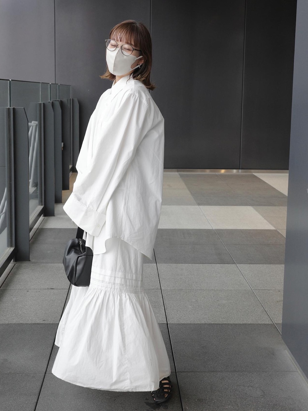 ホワイト系のシャツ/ブラウス、ホワイト系のスカート、ブラック系のハンドバッグを着用したレディースの春コーディネートの2枚目の写真