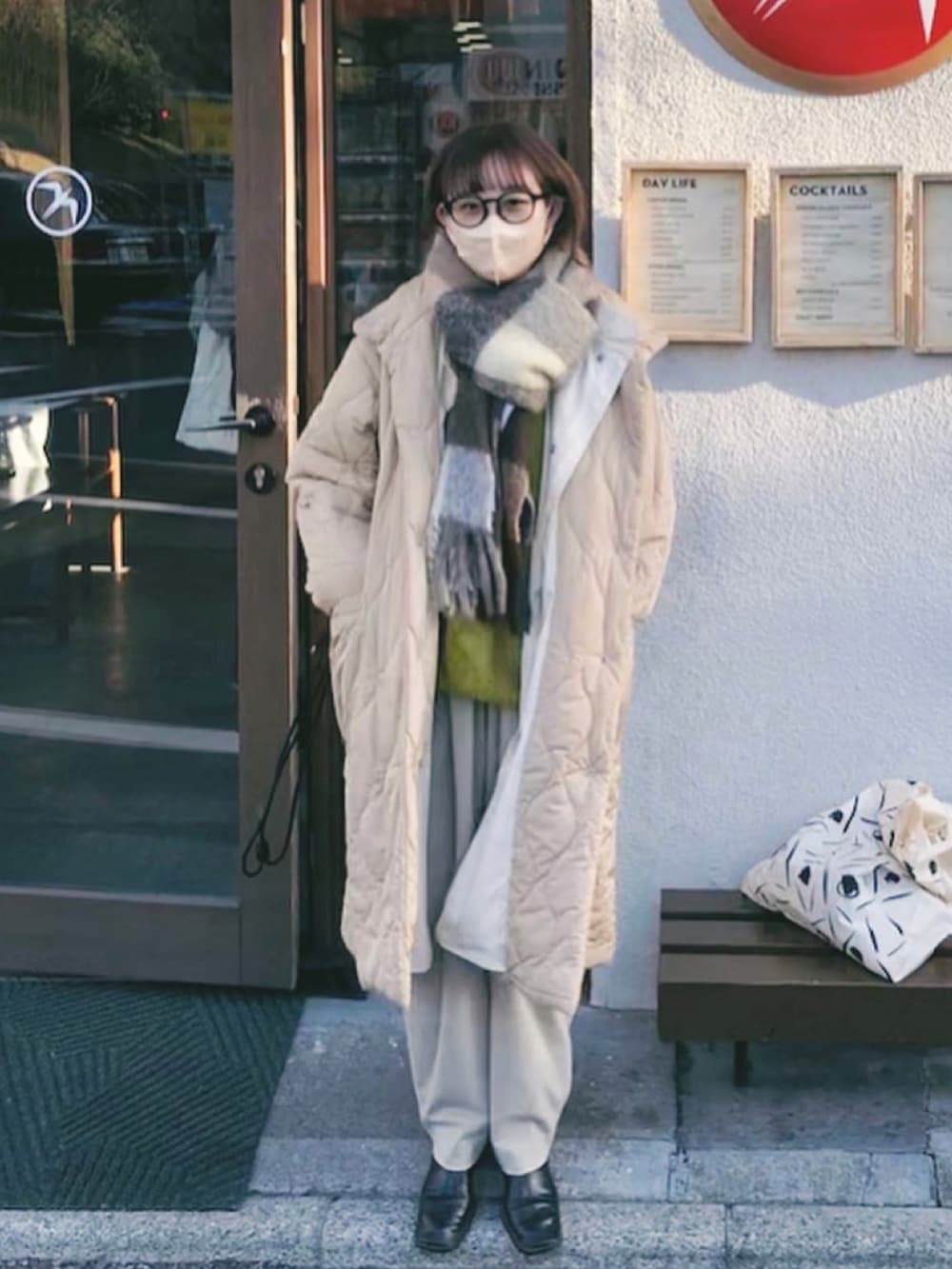 ベージュ系のジャケット/アウター、ベージュ系のマフラー、ブラウン系のメガネを着用したレディースの春コーディネートの2枚目の写真