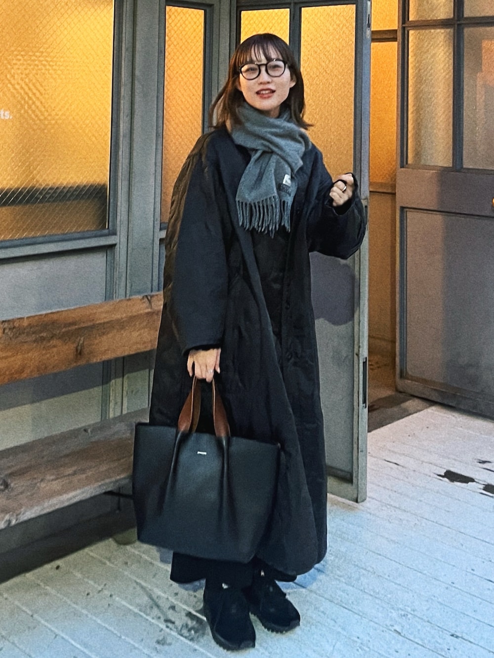 ブラック系のハンドバッグ、ブラック系のスニーカー、グレー系のマフラーを着用したレディースの春コーディネートの3枚目の写真