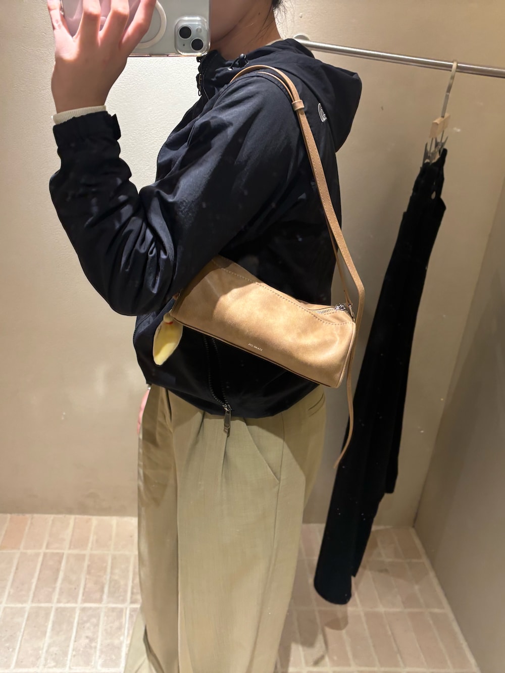 ブラック系のナイロンジャケット、ベージュ系のスラックス、ベージュ系のスニーカーを着用したレディースの秋コーディネートの2枚目の写真