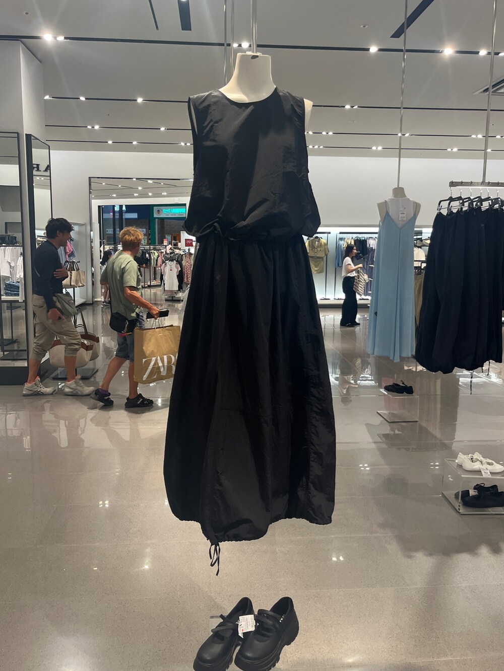 ブラック系のスカート、ブラック系のタンクトップ、レッド系のスニーカーを着用したレディースの夏コーディネートの3枚目の写真