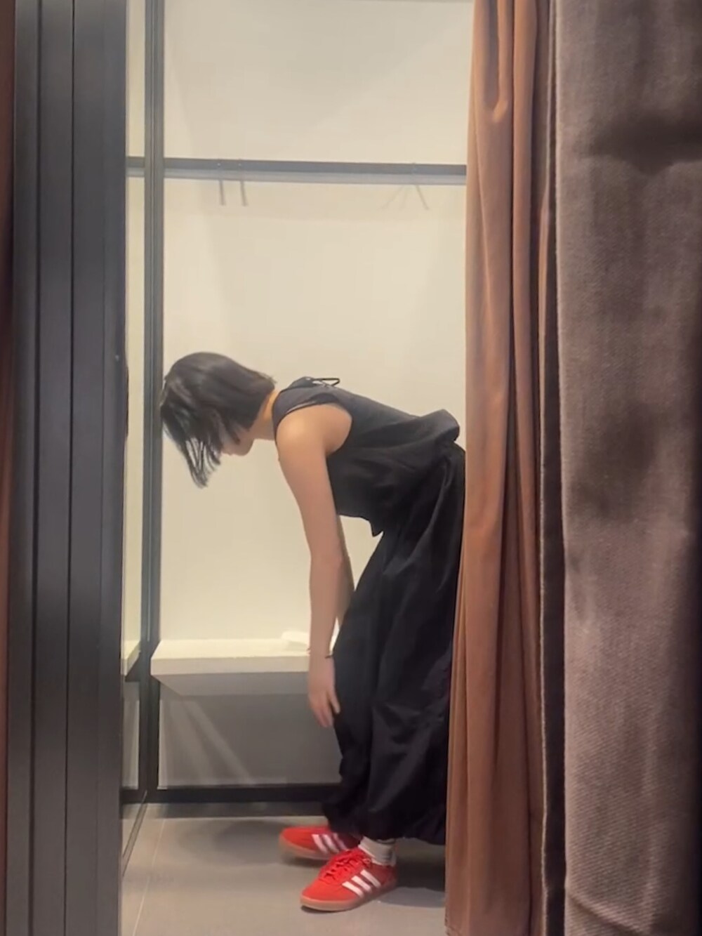 ブラック系のスカート、ブラック系のタンクトップ、レッド系のスニーカーを着用したレディースの夏コーディネートの2枚目の写真