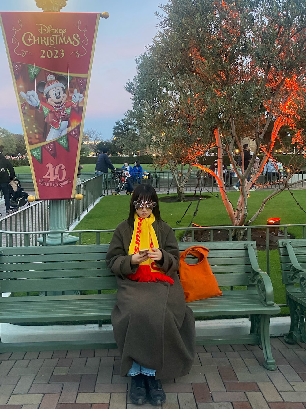 オレンジ系のトートバッグ、ブラウン系のジャケット/アウター、ブラック系のスニーカーを着用したレディースの冬コーディネートの4枚目の写真