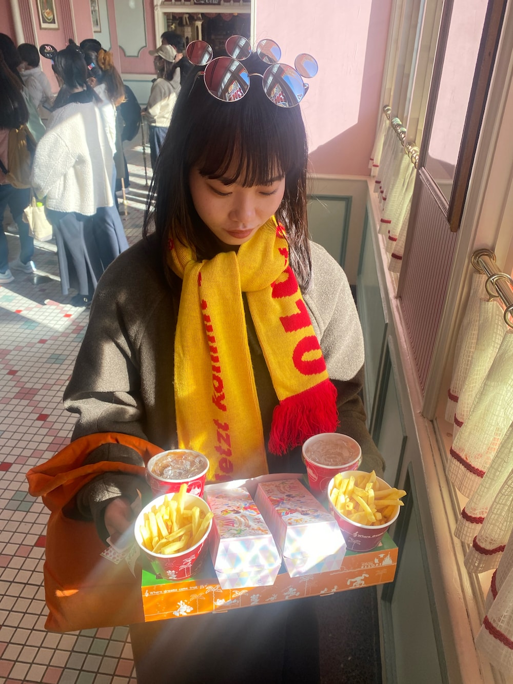 オレンジ系のトートバッグ、ブラウン系のジャケット/アウター、ブラック系のスニーカーを着用したレディースの冬コーディネートの3枚目の写真