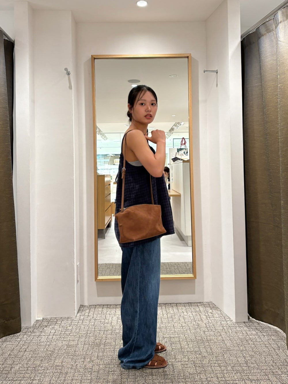 ブルー系のキャミソール、ブルー系のデニムパンツ、ブラウン系のショルダーバッグを着用したレディースの夏コーディネートの2枚目の写真