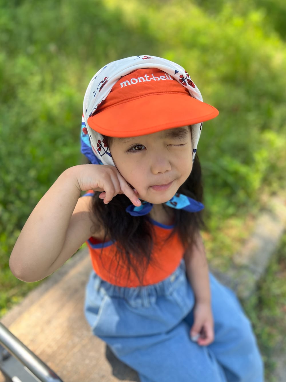 オレンジ系のタンクトップ、ブルー系のデニムパンツ、ブルー系のサンダルを着用したキッズの夏コーディネートの3枚目の写真