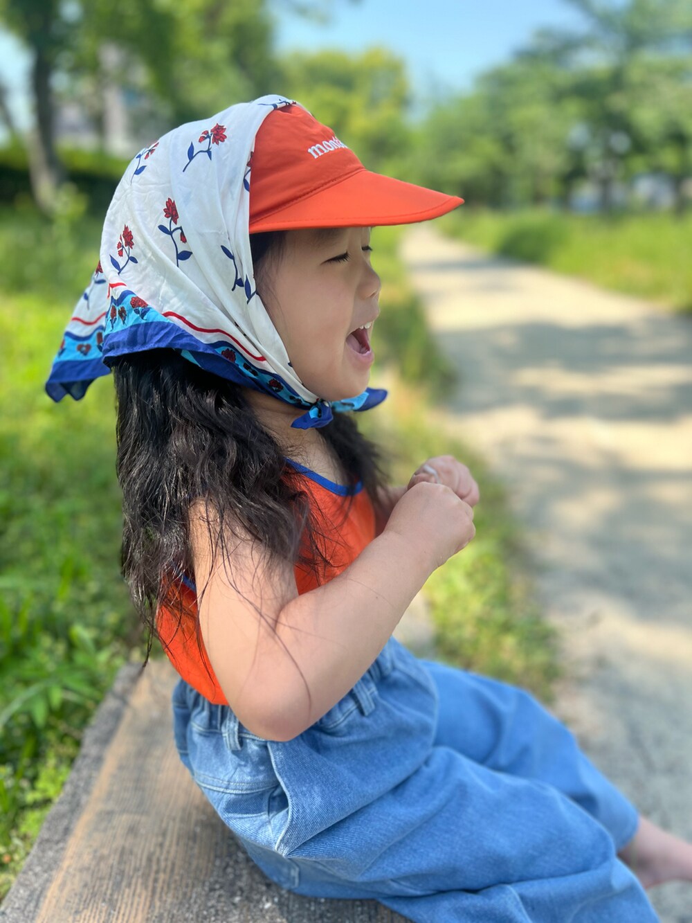 オレンジ系のタンクトップ、ブルー系のデニムパンツ、ブルー系のサンダルを着用したキッズの夏コーディネートの4枚目の写真