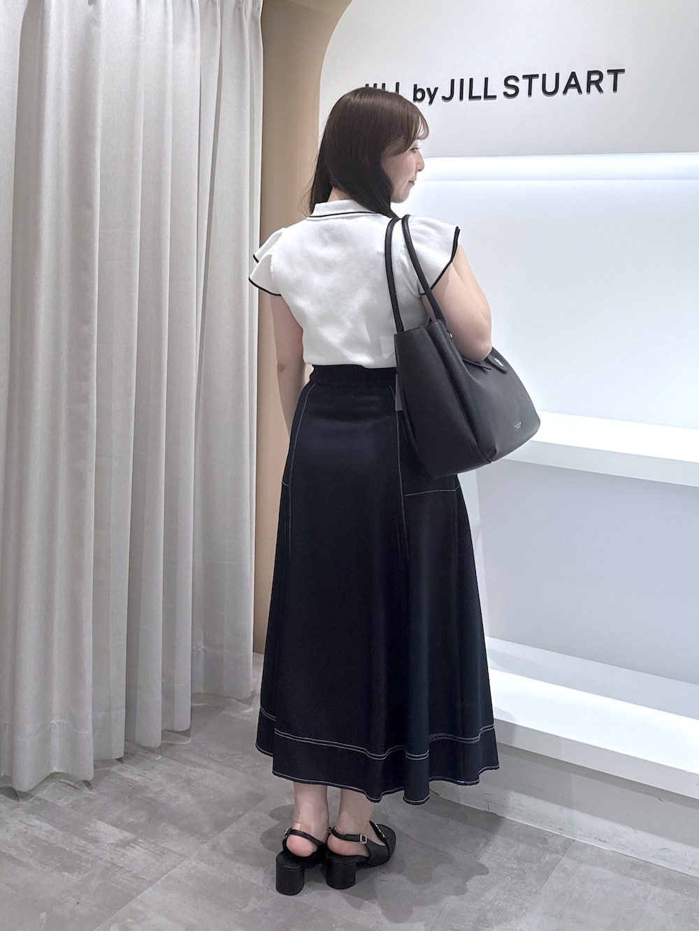 ホワイト系のニット/セーター、ブルー系のスカート、ブラック系のトートバッグを着用したレディースの夏コーディネートの3枚目の写真