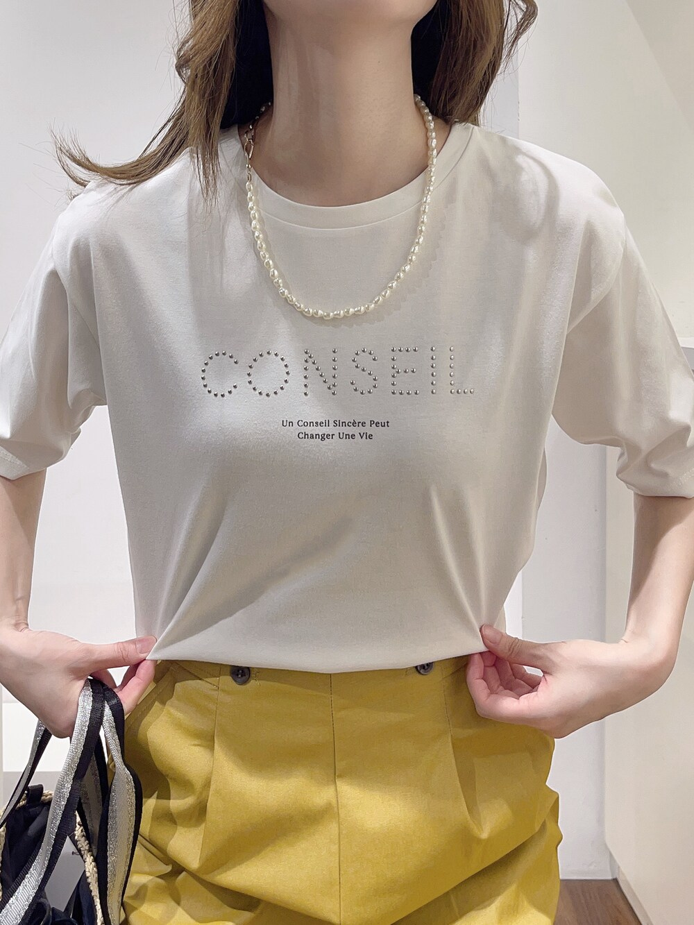 ホワイト系のTシャツ/カットソー、イエロー系のその他パンツ、ベージュ系のトートバッグを着用したレディースの春コーディネートの5枚目の写真