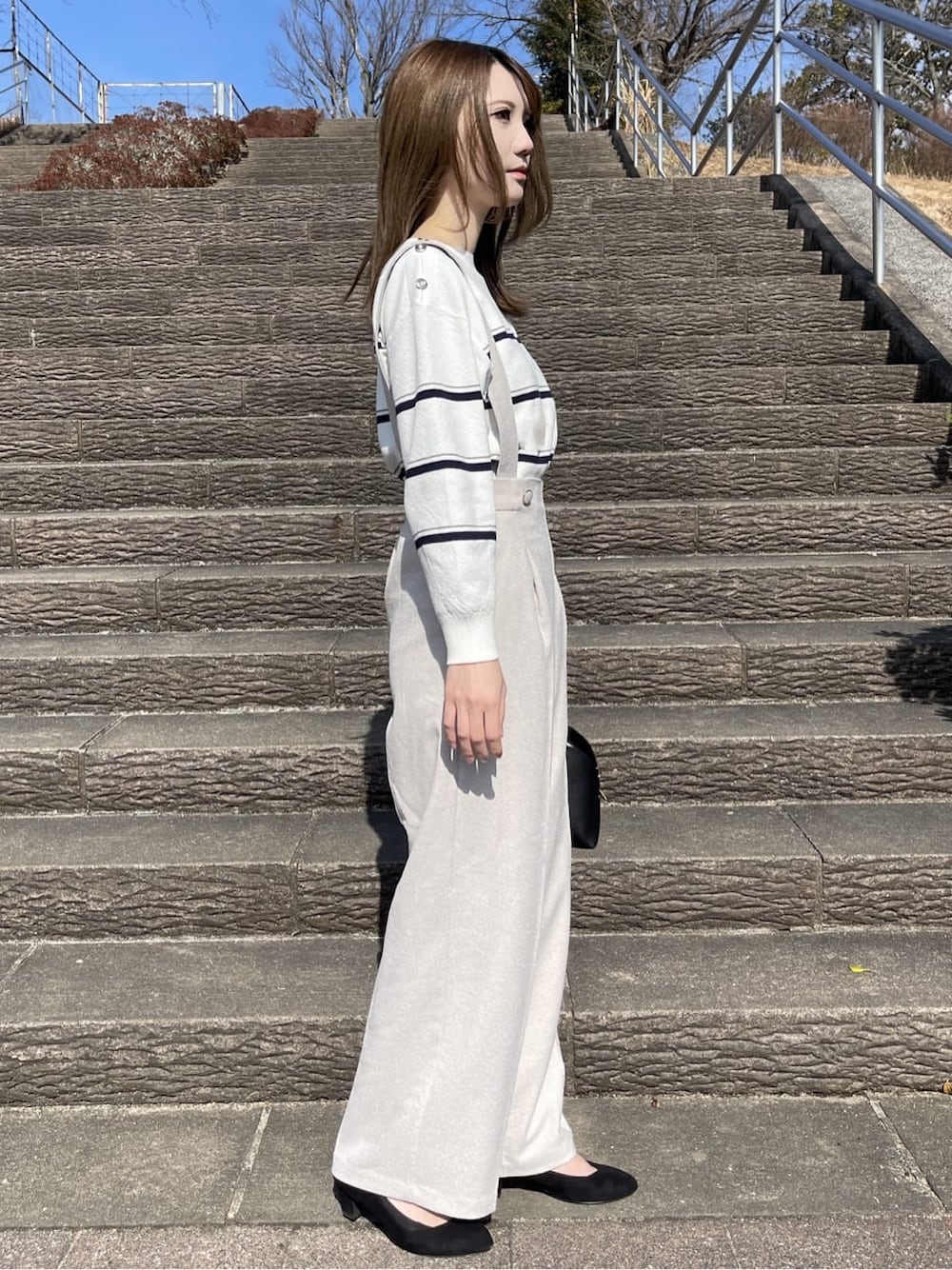 ホワイト系のニット/セーター、ベージュ系のその他パンツ、ブラック系のハンドバッグを着用したレディースの冬コーディネートの2枚目の写真