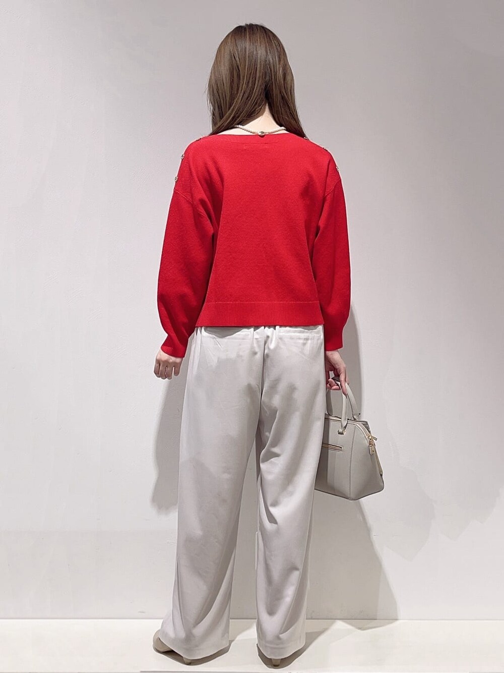 レッド系のニット/セーター、ベージュ系のその他パンツ、グレー系のトートバッグを着用したレディースの冬コーディネートの3枚目の写真