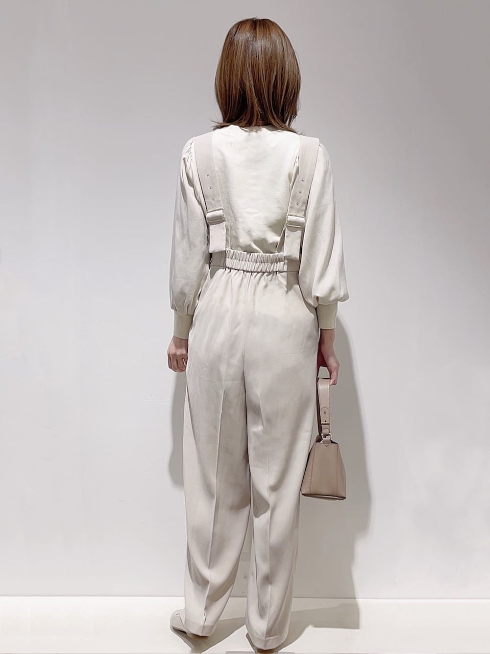 ホワイト系のニット/セーター、ベージュ系のサロペット/オーバーオール、ブラウン系のショルダーバッグを着用したレディースの冬コーディネートの3枚目の写真