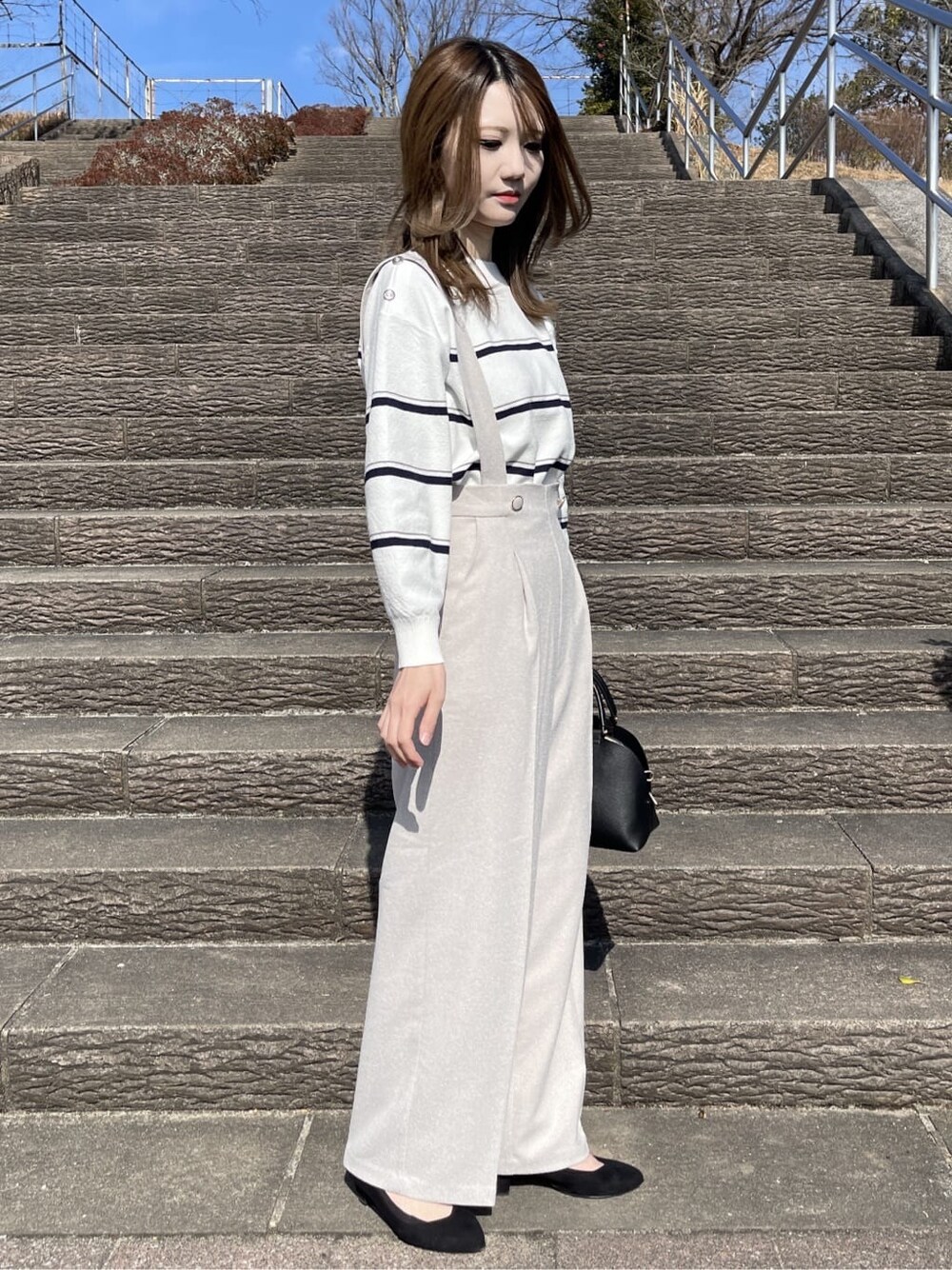 ホワイト系のニット/セーター、ベージュ系のその他パンツ、ブラック系のハンドバッグを着用したレディースの冬コーディネートの4枚目の写真