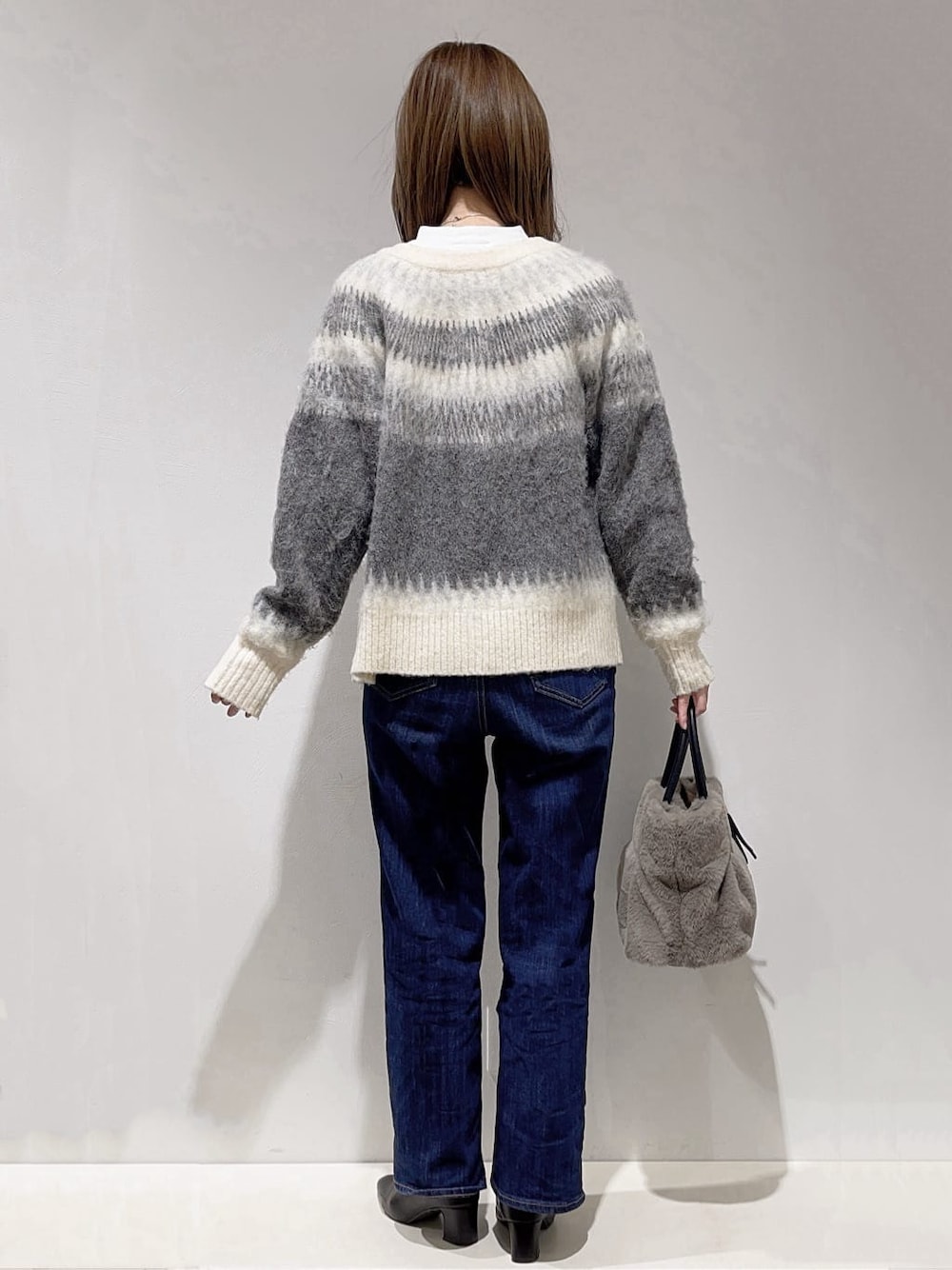 ブラック系のカーディガン/ボレロ、ホワイト系のTシャツ/カットソー、ブルー系のデニムパンツを着用したレディースの冬コーディネートの3枚目の写真