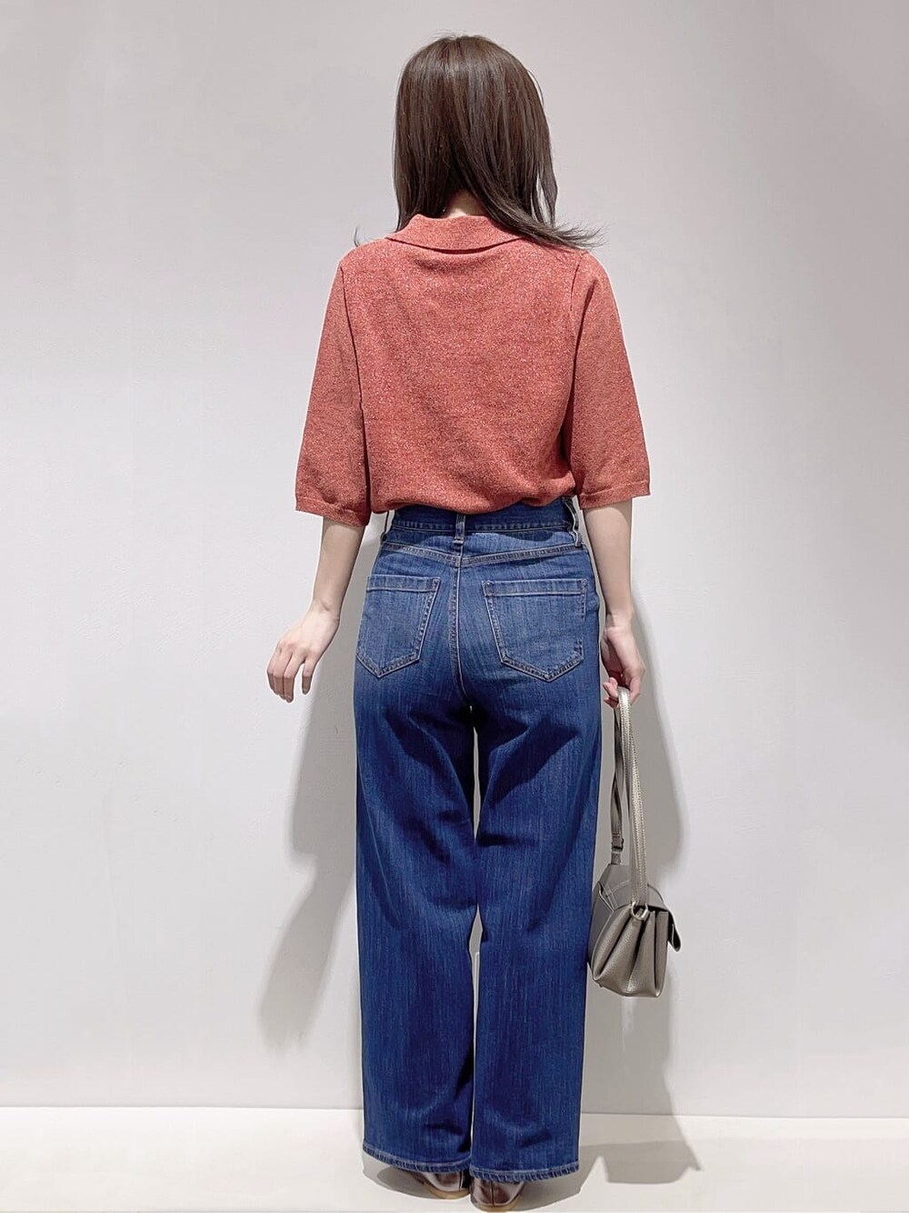 レッド系のニット/セーター、ブルー系のデニムパンツ、シルバー系のショルダーバッグを着用したレディースの秋コーディネートの3枚目の写真