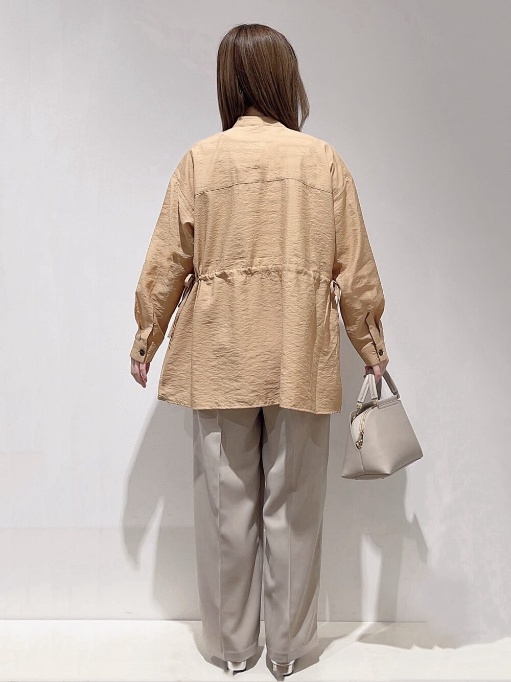 イエロー系のシャツ/ブラウス、ホワイト系のニット/セーター、ベージュ系のセットアップを着用したレディースの春コーディネートの3枚目の写真
