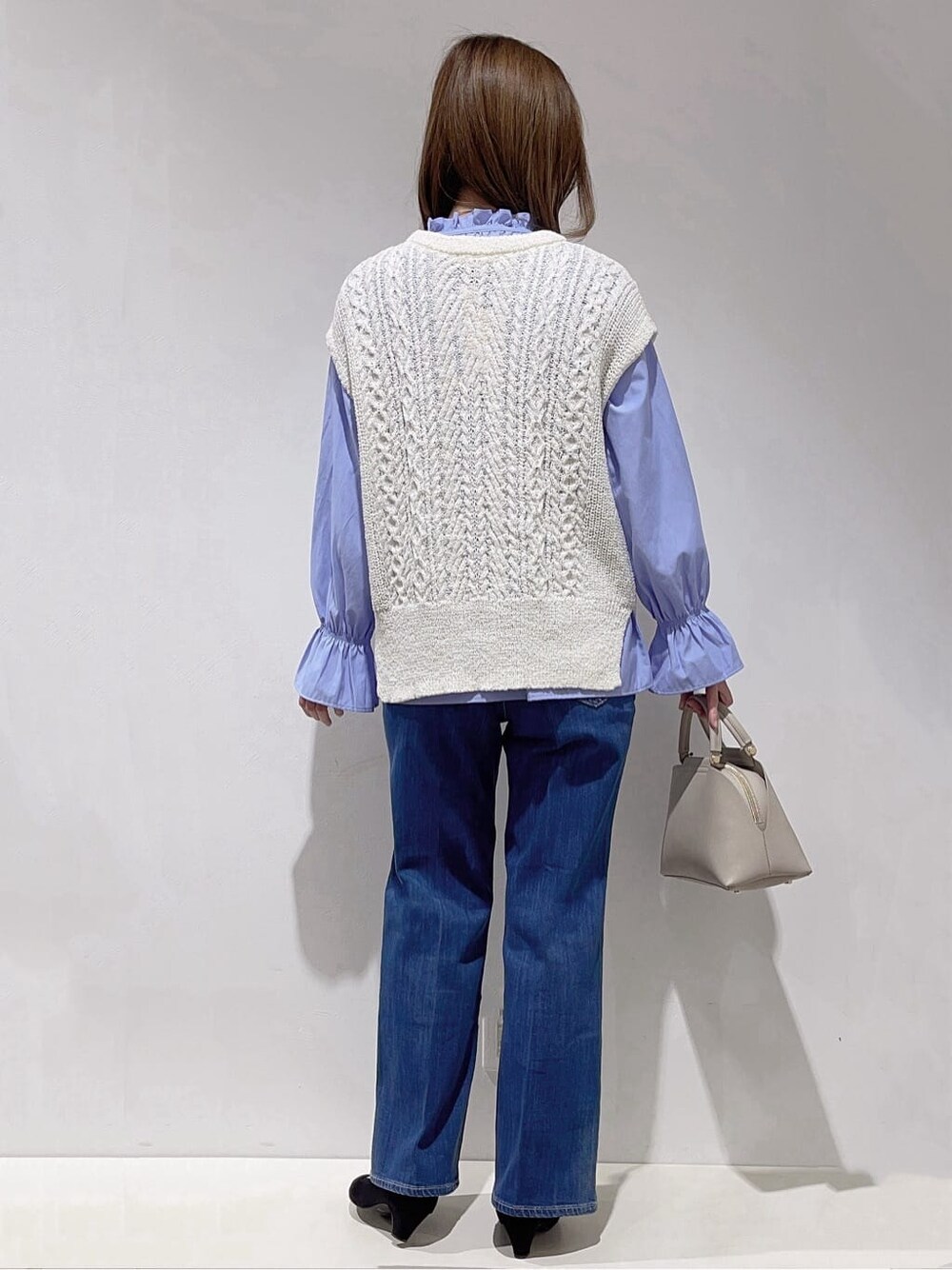 ホワイト系のニット/セーター、ブルー系のシャツ/ブラウス、ブルー系のデニムパンツを着用したレディースの冬コーディネートの3枚目の写真