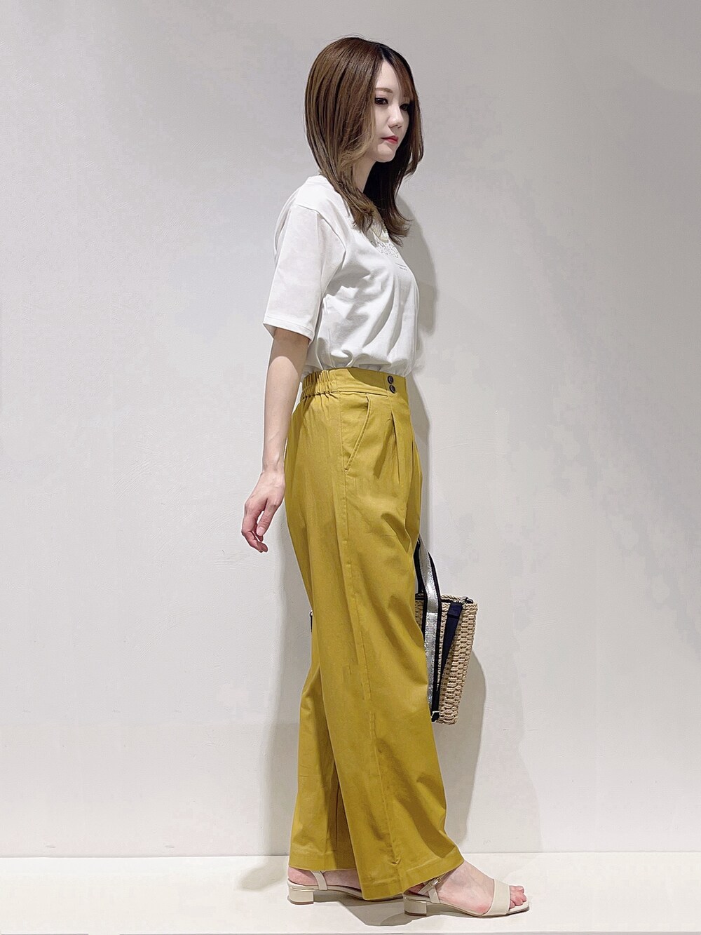 ホワイト系のTシャツ/カットソー、イエロー系のその他パンツ、ベージュ系のトートバッグを着用したレディースの春コーディネートの2枚目の写真