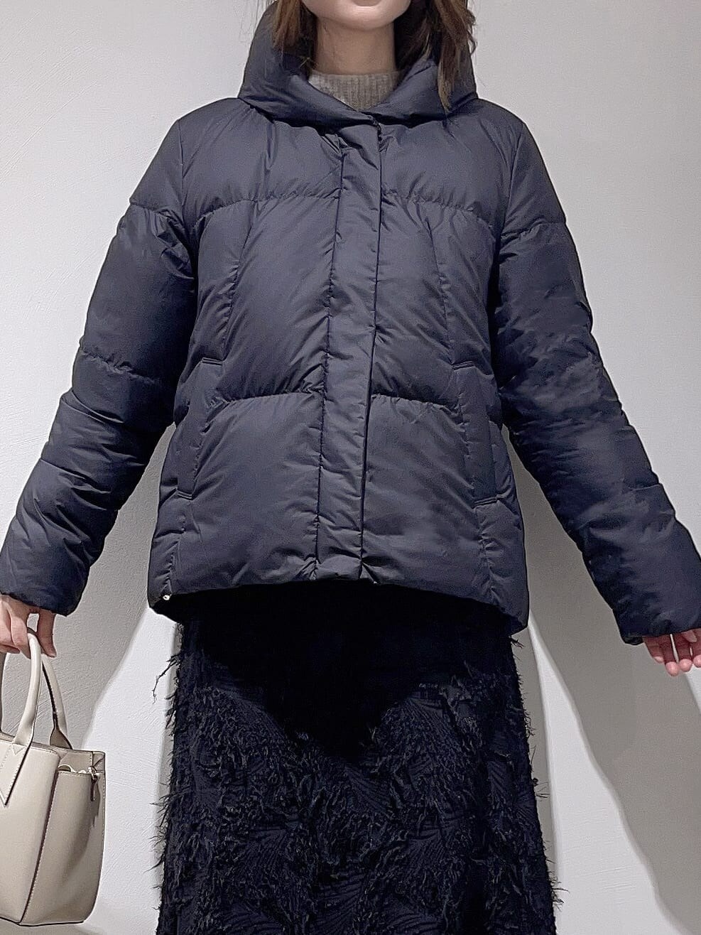 ブラック系のダウンジャケット/コート、ベージュ系のニット/セーター、ブラック系のスカートを着用したレディースの冬コーディネートの5枚目の写真