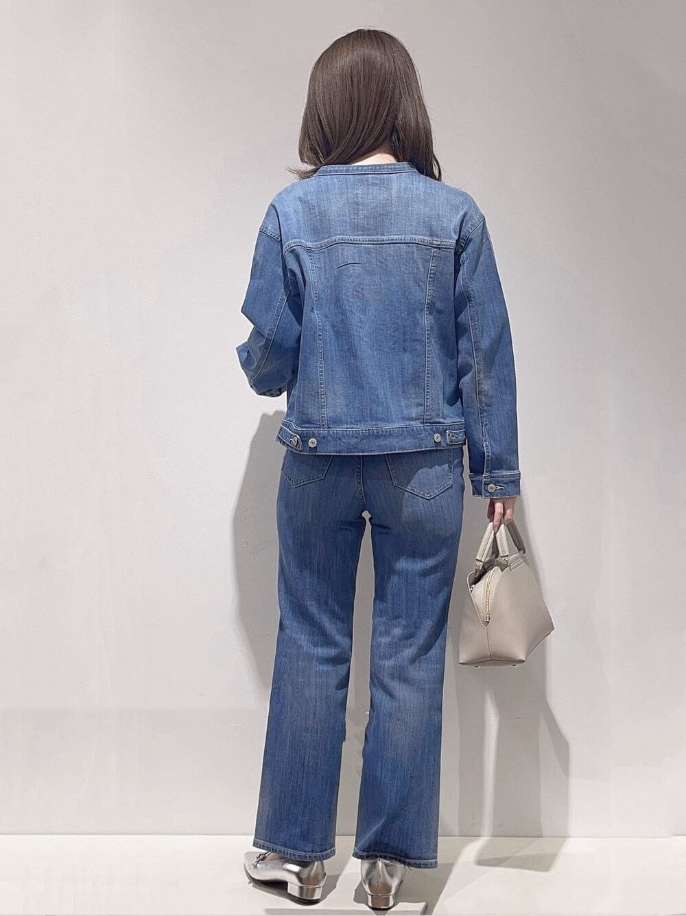 ブルー系のデニムジャケット、ブルー系のニット/セーター、ブルー系のデニムパンツを着用したレディースの春コーディネートの3枚目の写真