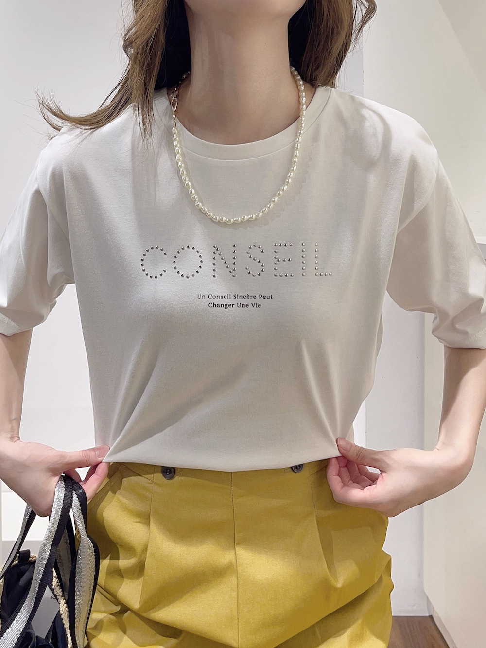 ベージュ系のトートバッグ、ブルー系のノーカラージャケット、ホワイト系のTシャツ/カットソーを着用したレディースの春コーディネートの5枚目の写真