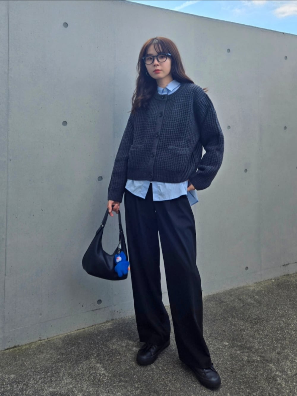 ブラック系のハンドバッグ、ブラック系のパンツ、グレー系のカーディガン/ボレロを着用したレディースの秋コーディネートの2枚目の写真