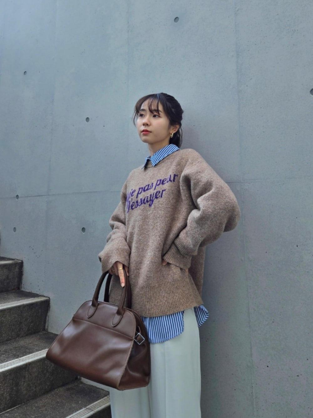 ブラウン系のニット/セーター、ブラウン系のボストンバッグ、ホワイト系のパンツを着用したレディースの冬コーディネートの5枚目の写真