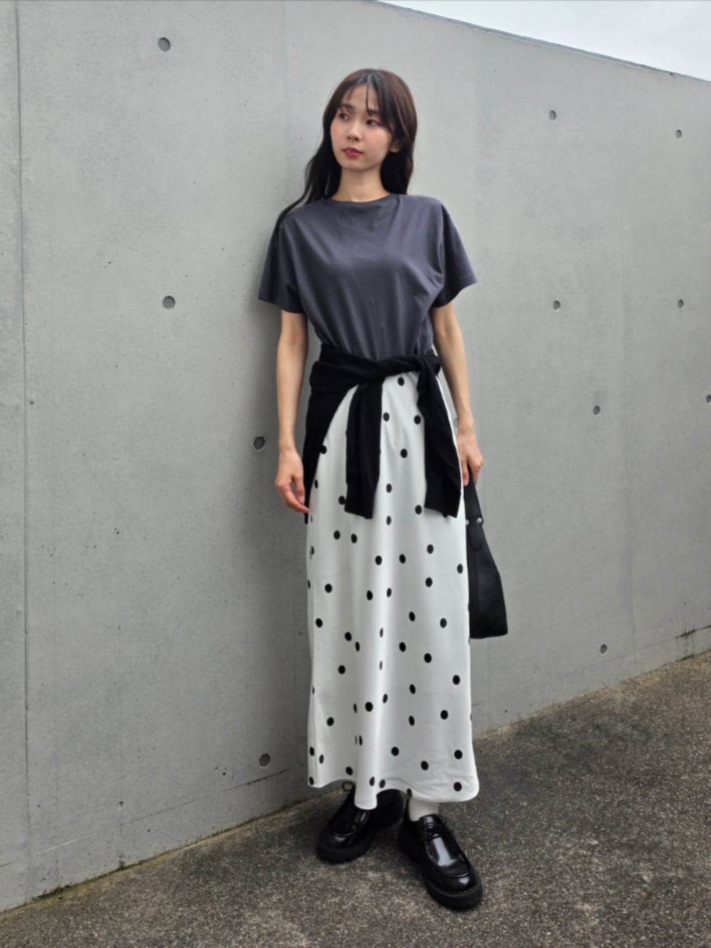 ブラック系のハンドバッグ、ホワイト系のスカート、グレー系のTシャツ/カットソーを着用したレディースの夏コーディネートの2枚目の写真