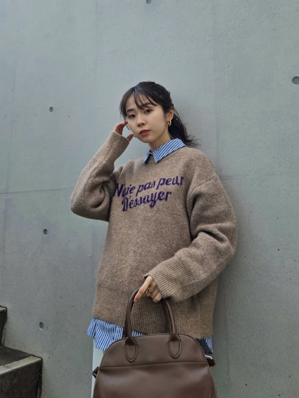 ブラウン系のニット/セーター、ブラウン系のボストンバッグ、ホワイト系のパンツを着用したレディースの冬コーディネートの3枚目の写真