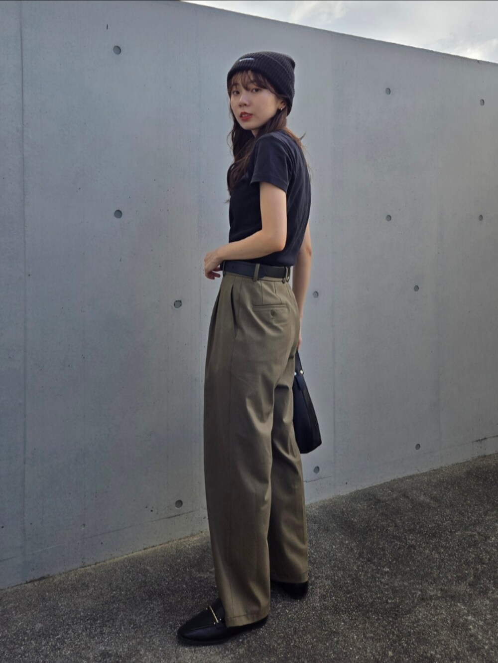 ブラック系のTシャツ/カットソー、ブラック系のハンドバッグ、グリーン系のパンツを着用したレディースの秋コーディネートの3枚目の写真