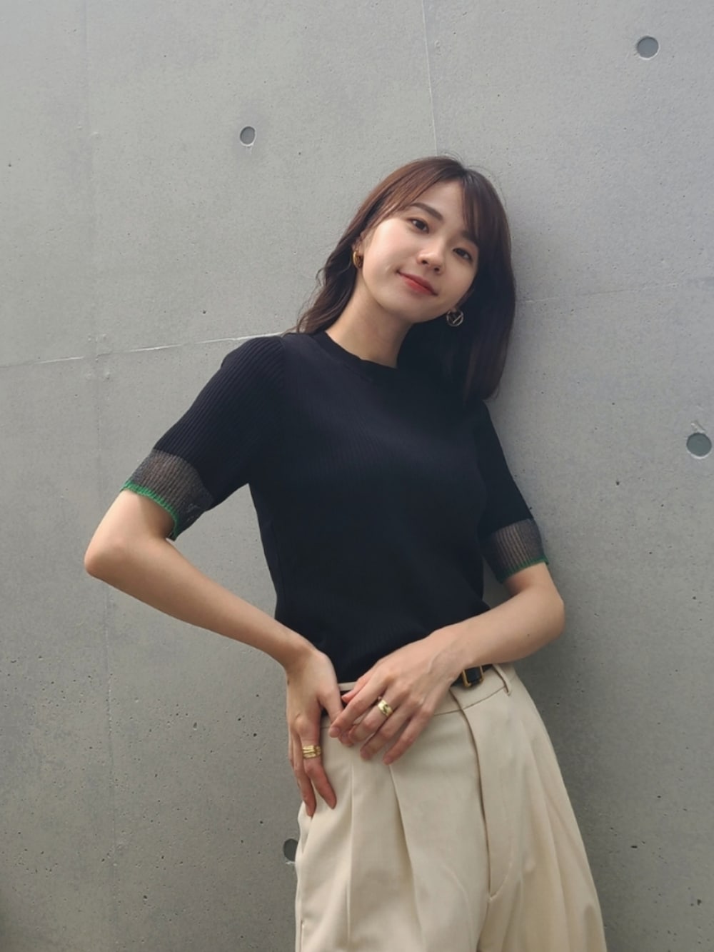 ブラック系のニット/セーター、ホワイト系のパンツ、ゴールド系のピアス（両耳用）を着用したレディースの夏コーディネートの3枚目の写真