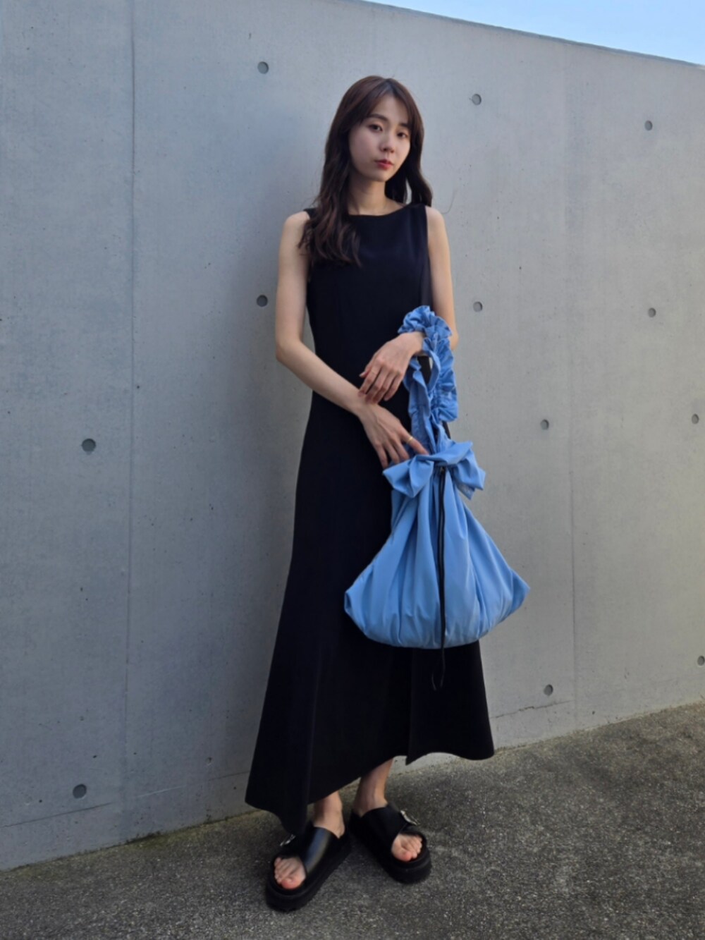 ブルー系のショルダーバッグ、ブラック系のサンダル、ブラック系のワンピースを着用したレディースの春コーディネートの2枚目の写真