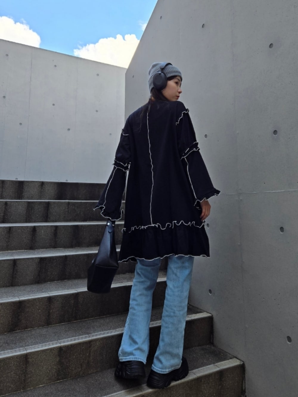 ブラック系のスニーカー、ブラック系のワンピース、ブルー系のデニムパンツを着用したレディースの秋コーディネートの3枚目の写真