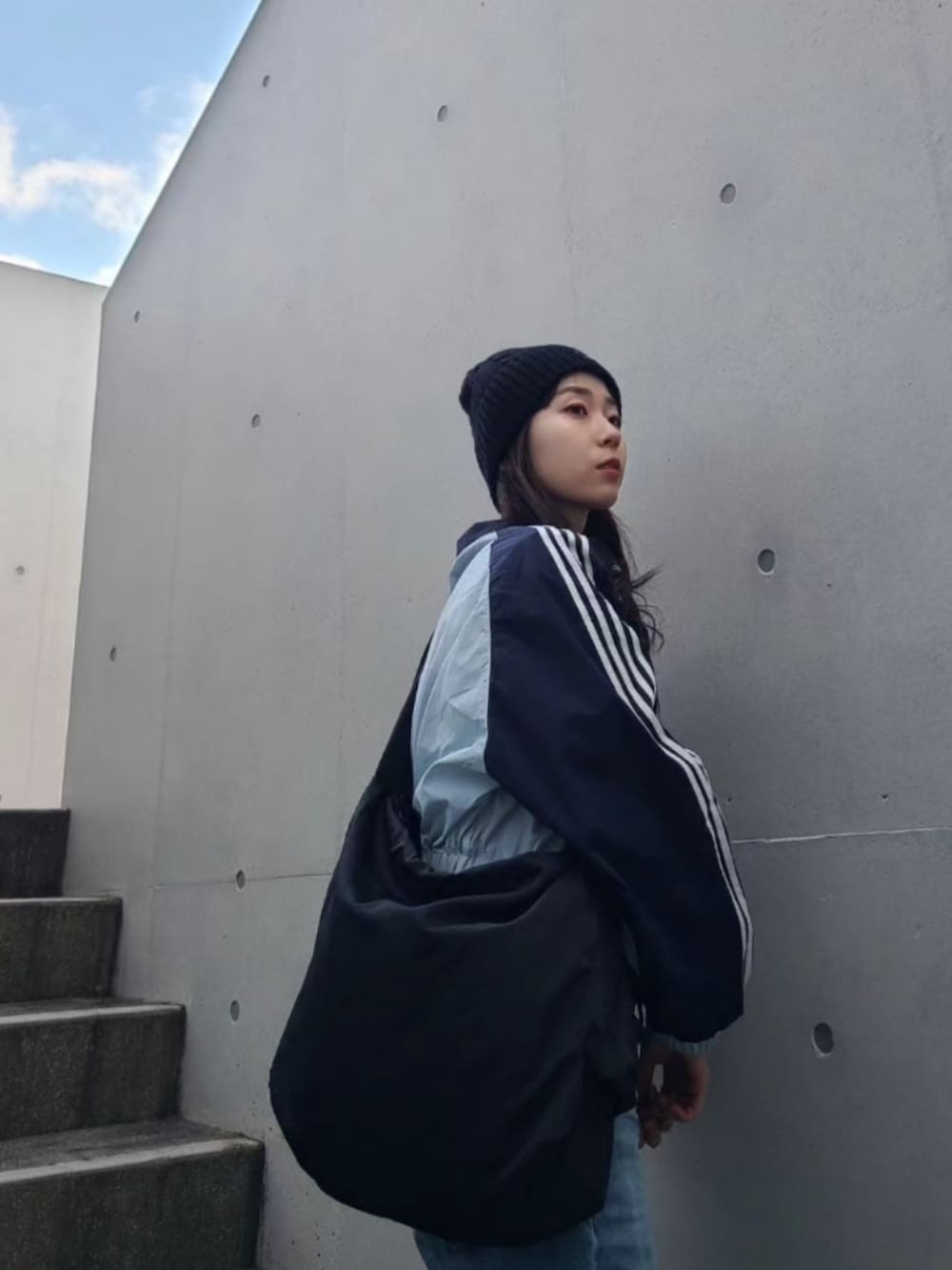 ブラック系のブーツ、ブルー系のナイロンジャケット、ブラック系のメッセンジャーバッグを着用したレディースの冬コーディネートの2枚目の写真