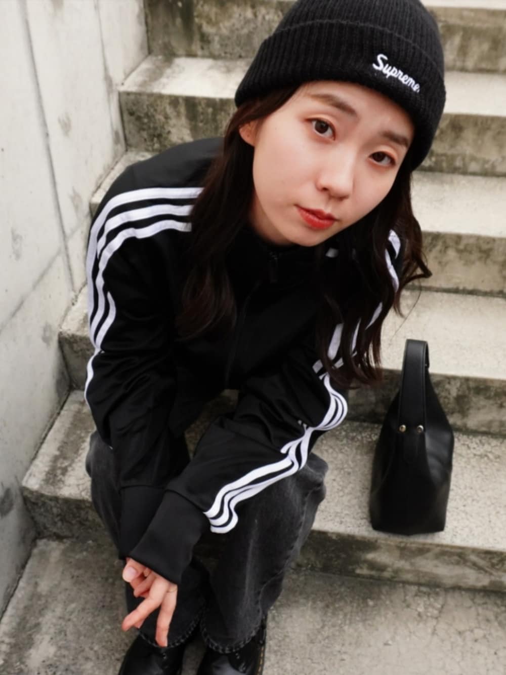 グレー系のデニムパンツ、ブラック系のハンドバッグ、ブラック系のジャージを着用したレディースの秋コーディネートの2枚目の写真