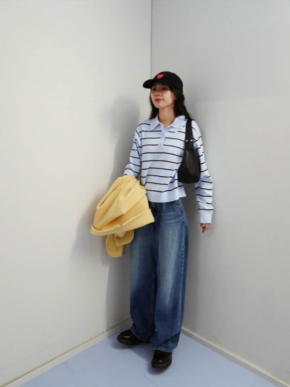 ブラック系のハンドバッグ、ブルー系のデニムパンツ、イエロー系のジャケット/アウターを着用したレディースの冬コーディネートの2枚目の写真