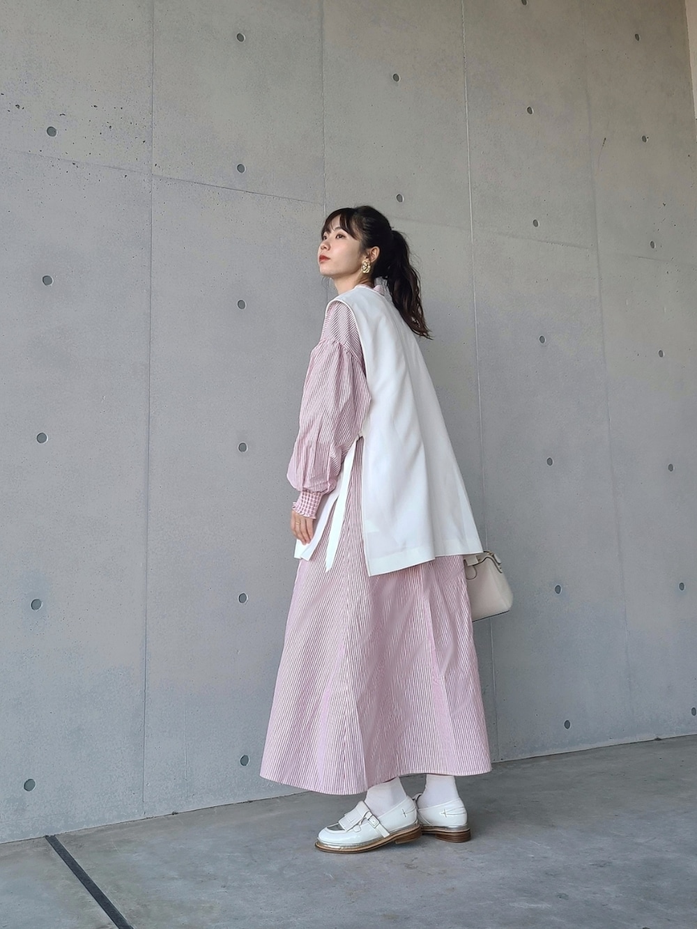 レッド系のシャツワンピース、ホワイト系のその他シューズ、ホワイト系のバッグを着用したレディースの冬コーディネートの2枚目の写真